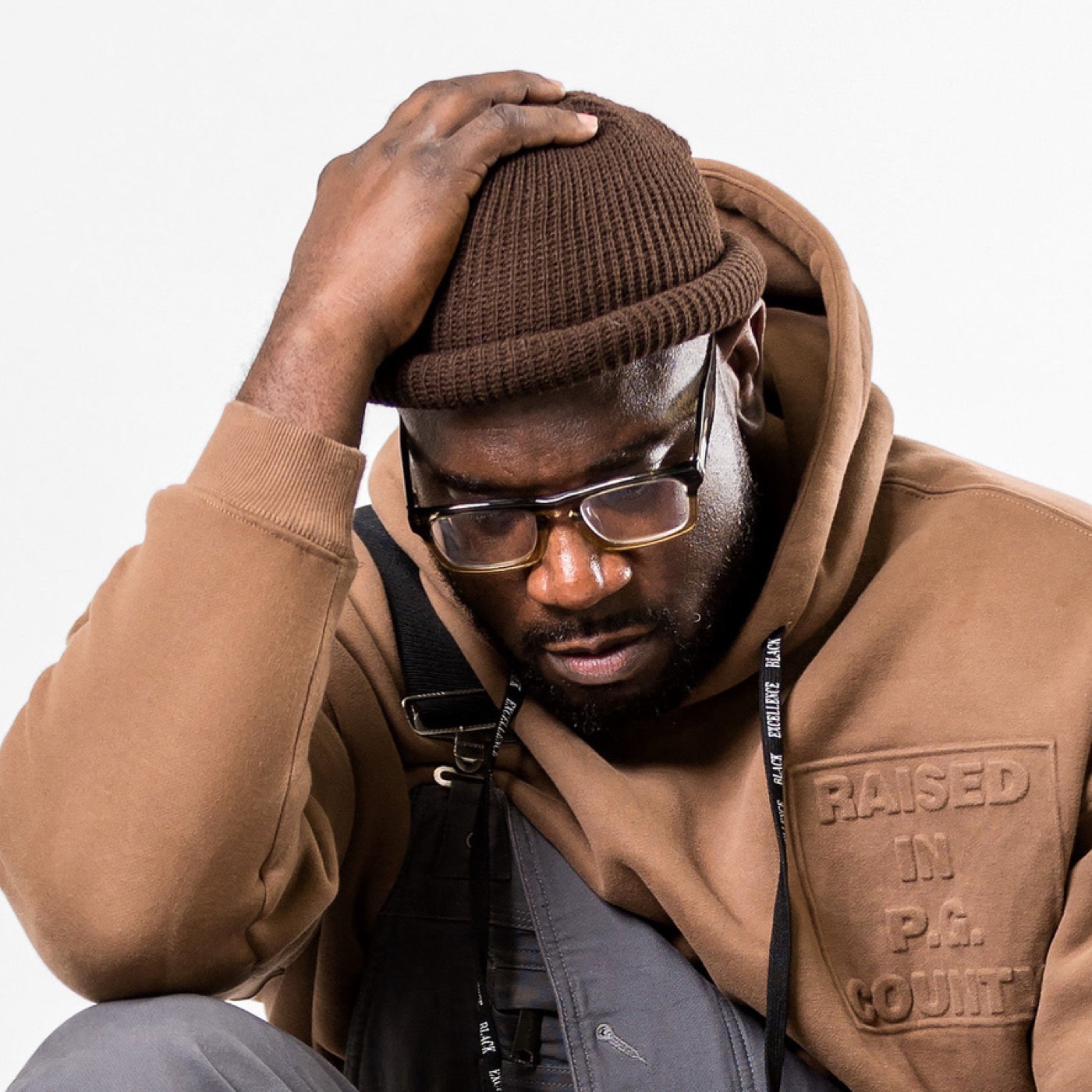 Alfred Duncan portrait — tan hoodie, brown beanie, glasses